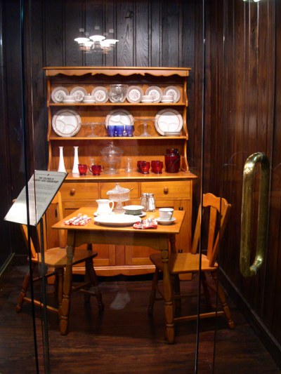 [Table with two chairs. Atop table is breakfast setup. In background is a china hutch.]